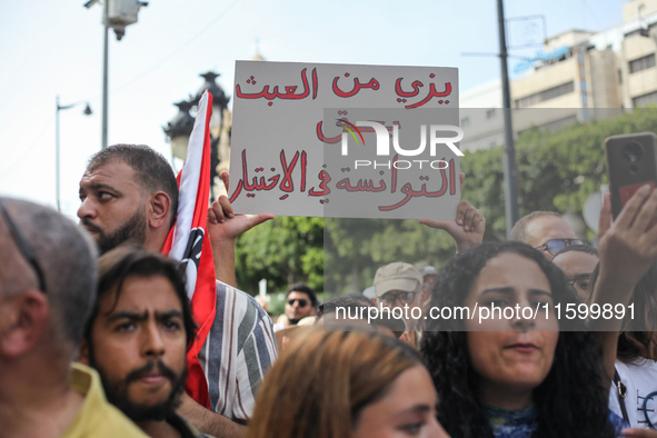 A demonstrator raises a placard that reads in Arabic, ''Stop making a mockery of the Tunisians' right to make their own choice,'' during a d...