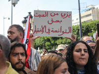 A demonstrator raises a placard that reads in Arabic, ''Stop making a mockery of the Tunisians' right to make their own choice,'' during a d...