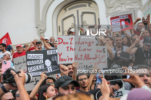 Demonstrators raise a placard that reads, ''Don't change the law you're not allowed,'' during a demonstration organized by the Tunisian Netw...