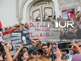 Demonstrators raise a placard that reads, ''Don't change the law you're not allowed,'' during a demonstration organized by the Tunisian Netw...