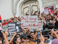 Demonstrators raise a placard that reads, ''Don't change the law you're not allowed,'' during a demonstration organized by the Tunisian Netw...