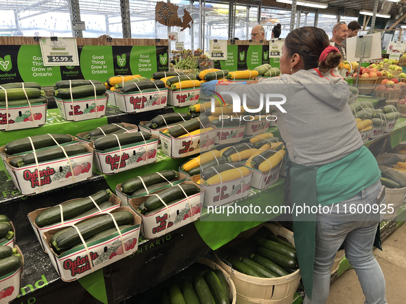 A worker places baskets of zucchinis on a shelf at a farmers market in Markham, Ontario, Canada, on September 22, 2024. 