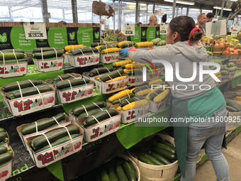 A worker places baskets of zucchinis on a shelf at a farmers market in Markham, Ontario, Canada, on September 22, 2024. (