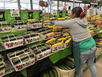 A worker places baskets of zucchinis on a shelf at a farmers market in Markham, Ontario, Canada, on September 22, 2024. (