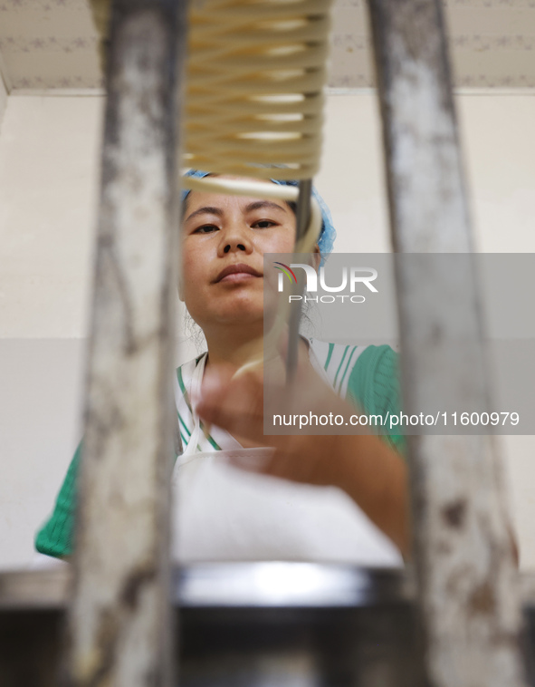 A worker processes hollow hanging noodles at a workshop in Suqian, Jiangsu province, China, on September 22, 2024. 