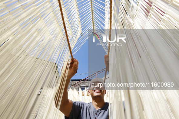 A worker processes hollow hanging noodles at a workshop in Suqian, Jiangsu province, China, on September 22, 2024. 