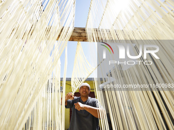 A worker processes hollow hanging noodles at a workshop in Suqian, Jiangsu province, China, on September 22, 2024. (