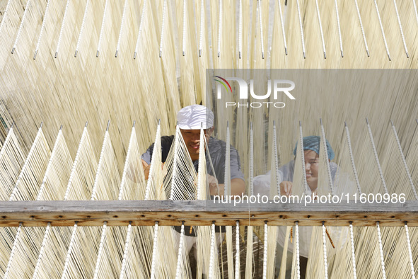 A worker processes hollow hanging noodles at a workshop in Suqian, Jiangsu province, China, on September 22, 2024. 