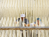 A worker processes hollow hanging noodles at a workshop in Suqian, Jiangsu province, China, on September 22, 2024. (