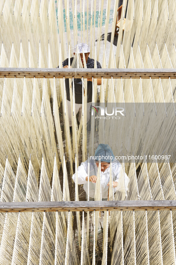 A worker processes hollow hanging noodles at a workshop in Suqian, Jiangsu province, China, on September 22, 2024. 