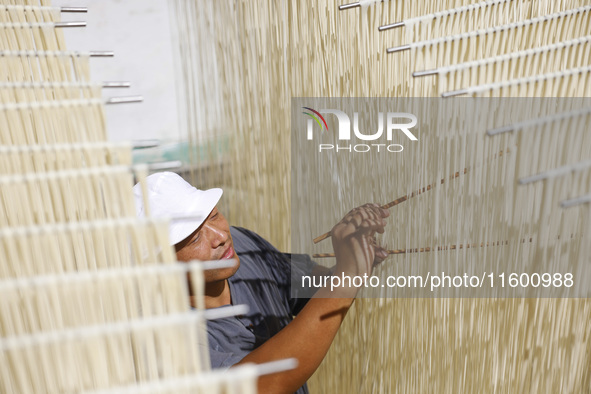 A worker processes hollow hanging noodles at a workshop in Suqian, Jiangsu province, China, on September 22, 2024. 