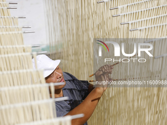 A worker processes hollow hanging noodles at a workshop in Suqian, Jiangsu province, China, on September 22, 2024. (