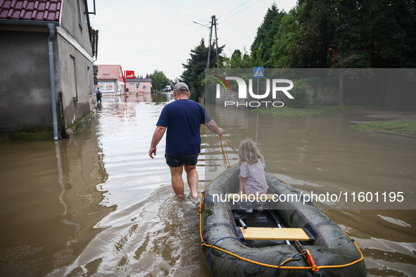 A man with a girl and a raft are seen in the water after Nysa Klodzka river flooded town of Lewin Brzeski in southwestern Poland, on Septemb...