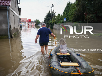 A man with a girl and a raft are seen in the water after Nysa Klodzka river flooded town of Lewin Brzeski in southwestern Poland, on Septemb...