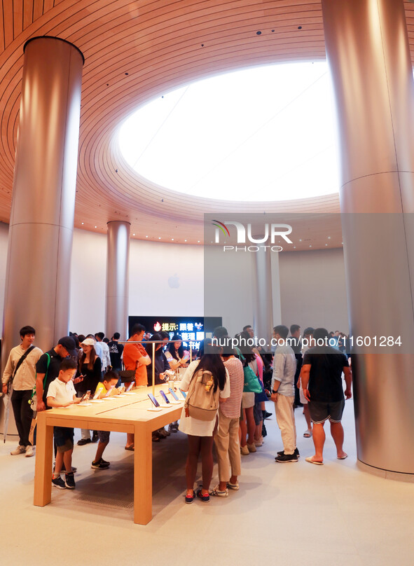 Customers experience Apple's new flagship mobile phone, the iPhone 16, at the largest Apple flagship store in Asia in Shanghai, China, on Se...