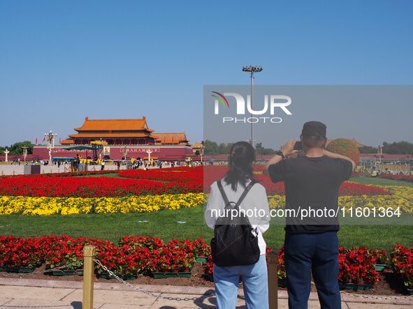 Tourists pose for a group photo in front of the flower beds at Tian 'anmen Square to celebrate the upcoming National Day in Beijing, China,...