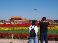 Tourists pose for a group photo in front of the flower beds at Tian 'anmen Square to celebrate the upcoming National Day in Beijing, China,...