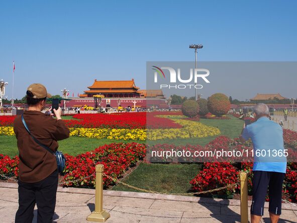 Tourists pose for a group photo in front of the flower beds at Tian 'anmen Square to celebrate the upcoming National Day in Beijing, China,...