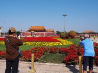 Tourists pose for a group photo in front of the flower beds at Tian 'anmen Square to celebrate the upcoming National Day in Beijing, China,...