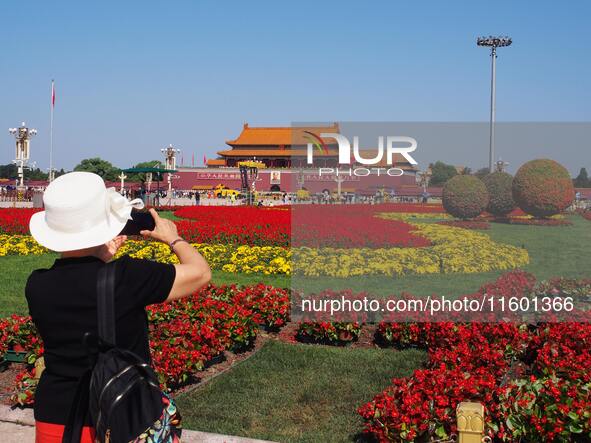 Tourists pose for a group photo in front of the flower beds at Tian 'anmen Square to celebrate the upcoming National Day in Beijing, China,...