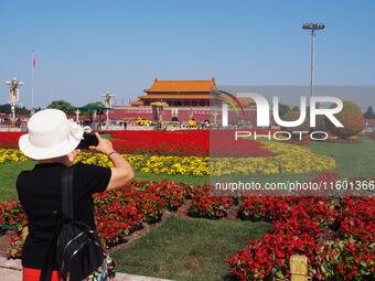 Tourists pose for a group photo in front of the flower beds at Tian 'anmen Square to celebrate the upcoming National Day in Beijing, China,...