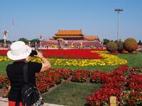 Tourists pose for a group photo in front of the flower beds at Tian 'anmen Square to celebrate the upcoming National Day in Beijing, China,...