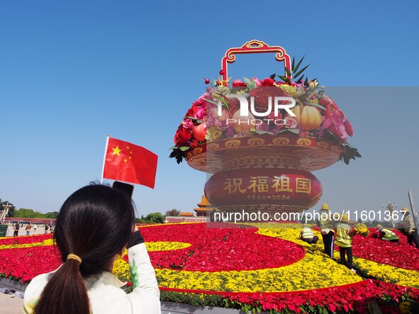 Tourists pose for a group photo in front of the flower beds at Tian 'anmen Square to celebrate the upcoming National Day in Beijing, China,...