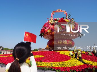 Tourists pose for a group photo in front of the flower beds at Tian 'anmen Square to celebrate the upcoming National Day in Beijing, China,...