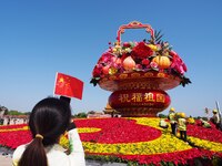 Tourists pose for a group photo in front of the flower beds at Tian 'anmen Square to celebrate the upcoming National Day in Beijing, China,...