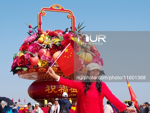 Tourists pose for a group photo in front of the flower beds at Tian 'anmen Square to celebrate the upcoming National Day in Beijing, China,...