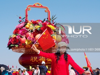 Tourists pose for a group photo in front of the flower beds at Tian 'anmen Square to celebrate the upcoming National Day in Beijing, China,...