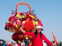 Tourists pose for a group photo in front of the flower beds at Tian 'anmen Square to celebrate the upcoming National Day in Beijing, China,...