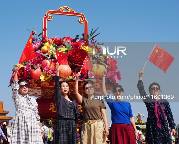 Tourists pose for a group photo in front of the flower beds at Tian 'anmen Square to celebrate the upcoming National Day in Beijing, China,...