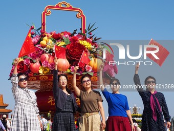 Tourists pose for a group photo in front of the flower beds at Tian 'anmen Square to celebrate the upcoming National Day in Beijing, China,...