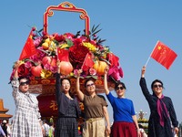 Tourists pose for a group photo in front of the flower beds at Tian 'anmen Square to celebrate the upcoming National Day in Beijing, China,...