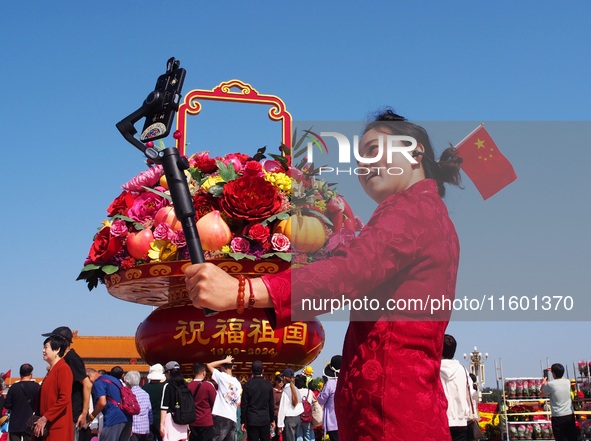 Tourists pose for a group photo in front of the flower beds at Tian 'anmen Square to celebrate the upcoming National Day in Beijing, China,...