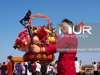 Tourists pose for a group photo in front of the flower beds at Tian 'anmen Square to celebrate the upcoming National Day in Beijing, China,...