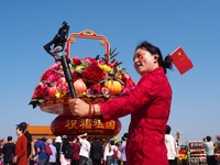 Tourists pose for a group photo in front of the flower beds at Tian 'anmen Square to celebrate the upcoming National Day in Beijing, China,...