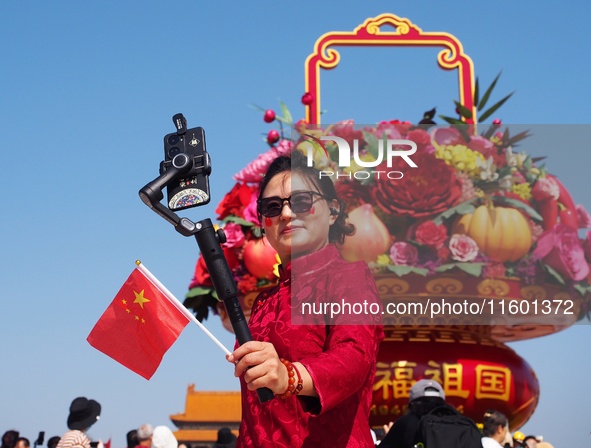 Tourists pose for a group photo in front of the flower beds at Tian 'anmen Square to celebrate the upcoming National Day in Beijing, China,...