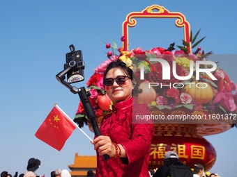 Tourists pose for a group photo in front of the flower beds at Tian 'anmen Square to celebrate the upcoming National Day in Beijing, China,...