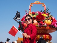 Tourists pose for a group photo in front of the flower beds at Tian 'anmen Square to celebrate the upcoming National Day in Beijing, China,...