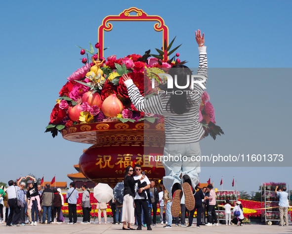 Tourists pose for a group photo in front of the flower beds at Tian 'anmen Square to celebrate the upcoming National Day in Beijing, China,...