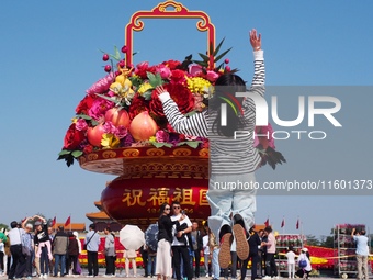 Tourists pose for a group photo in front of the flower beds at Tian 'anmen Square to celebrate the upcoming National Day in Beijing, China,...