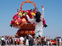 Tourists pose for a group photo in front of the flower beds at Tian 'anmen Square to celebrate the upcoming National Day in Beijing, China,...