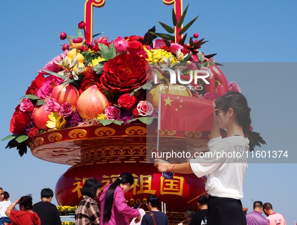 Tourists pose for a group photo in front of the flower beds at Tian 'anmen Square to celebrate the upcoming National Day in Beijing, China,...