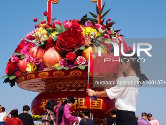 Tourists pose for a group photo in front of the flower beds at Tian 'anmen Square to celebrate the upcoming National Day in Beijing, China,...