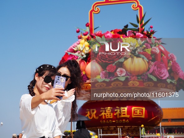 Tourists pose for a group photo in front of the flower beds at Tian 'anmen Square to celebrate the upcoming National Day in Beijing, China,...