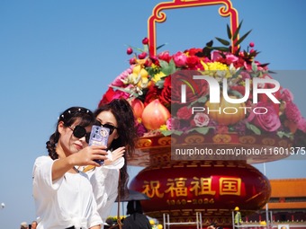 Tourists pose for a group photo in front of the flower beds at Tian 'anmen Square to celebrate the upcoming National Day in Beijing, China,...