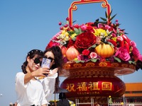 Tourists pose for a group photo in front of the flower beds at Tian 'anmen Square to celebrate the upcoming National Day in Beijing, China,...