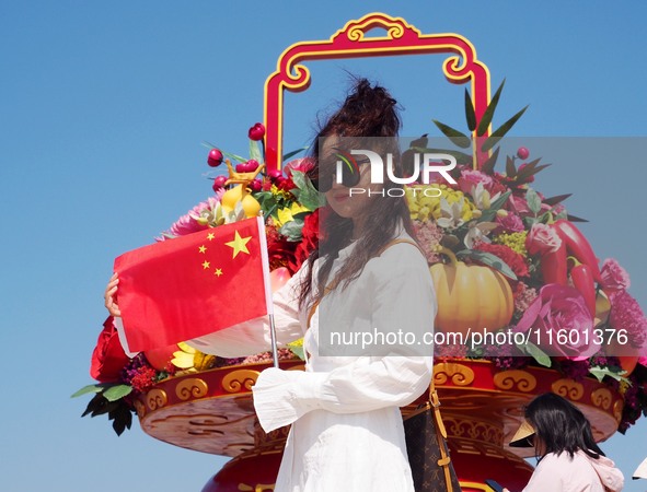 Tourists pose for a group photo in front of the flower beds at Tian 'anmen Square to celebrate the upcoming National Day in Beijing, China,...